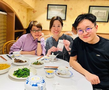 Three people smiling around a restaurant table with dishes in front of them