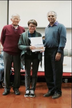 A woman holding a certificate while standing between two men